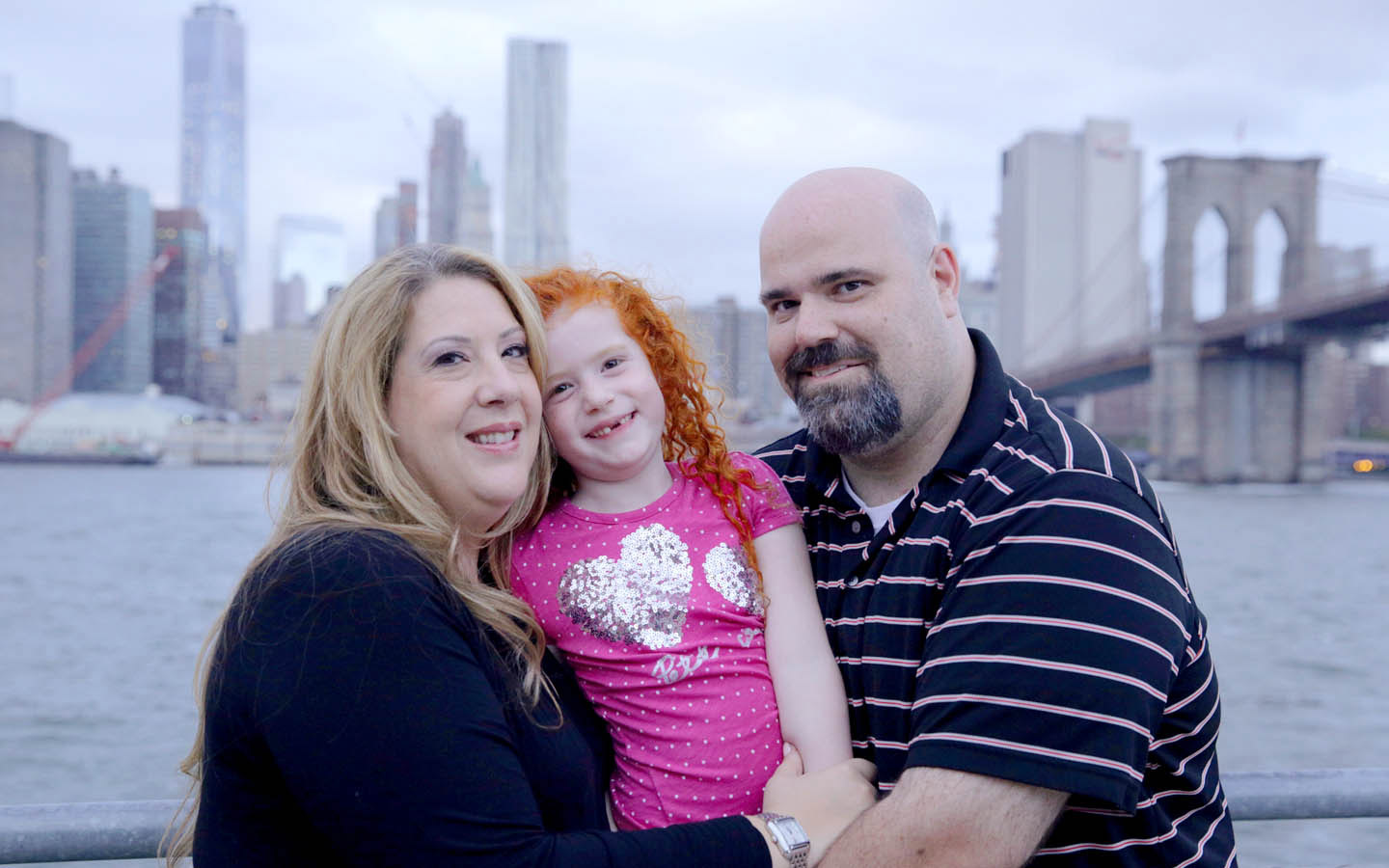A family with a hearing implant and member of the Cochlear family program pose together 