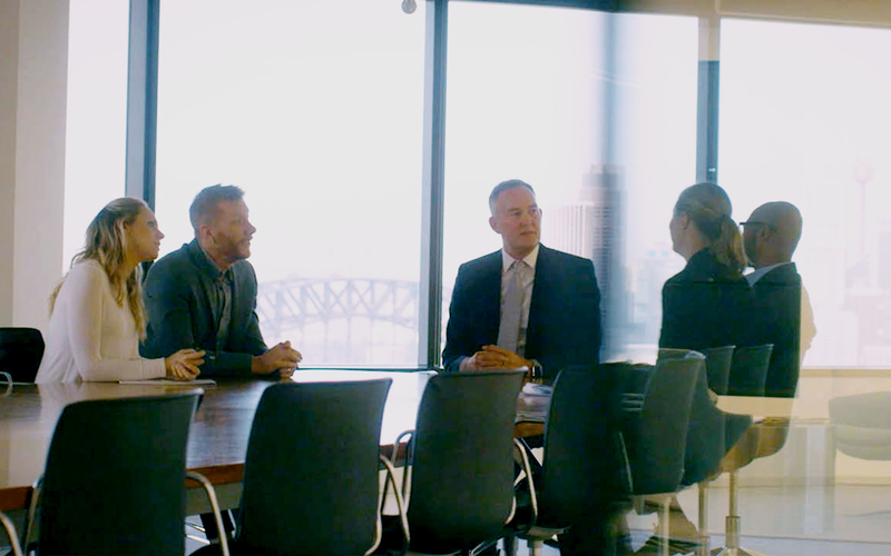 Cochlear recipient Tobin speaks to workers during a meeting in an office