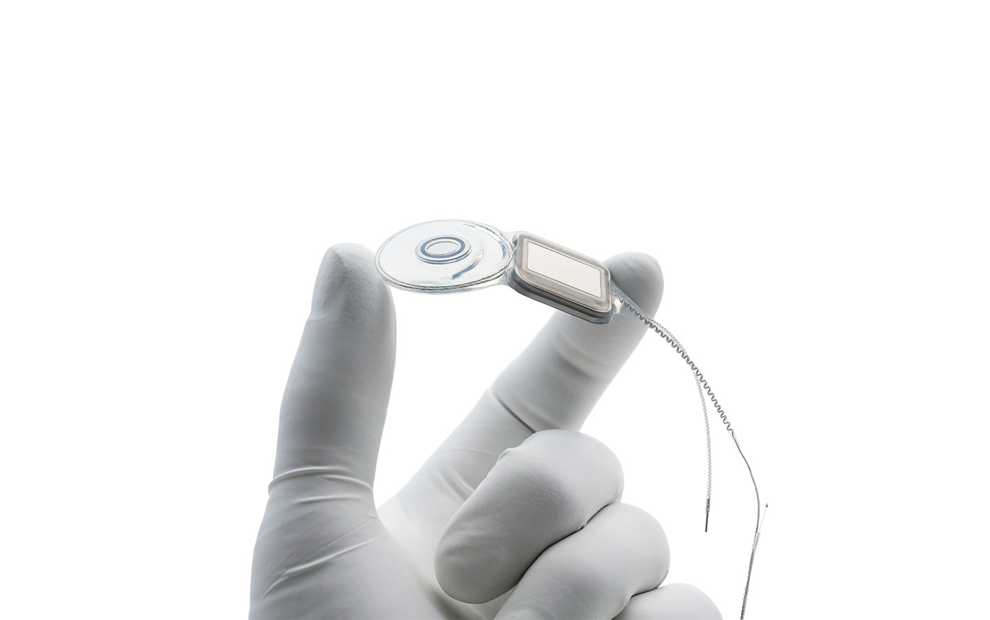 Hand eines Chirurgen mit Latexhandschuh hält ein Nucleus Implantat