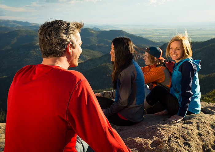 Il portatore di impianto Mathias e la sua famiglia siedono insieme sulla cima di una montagna dopo un’escursione