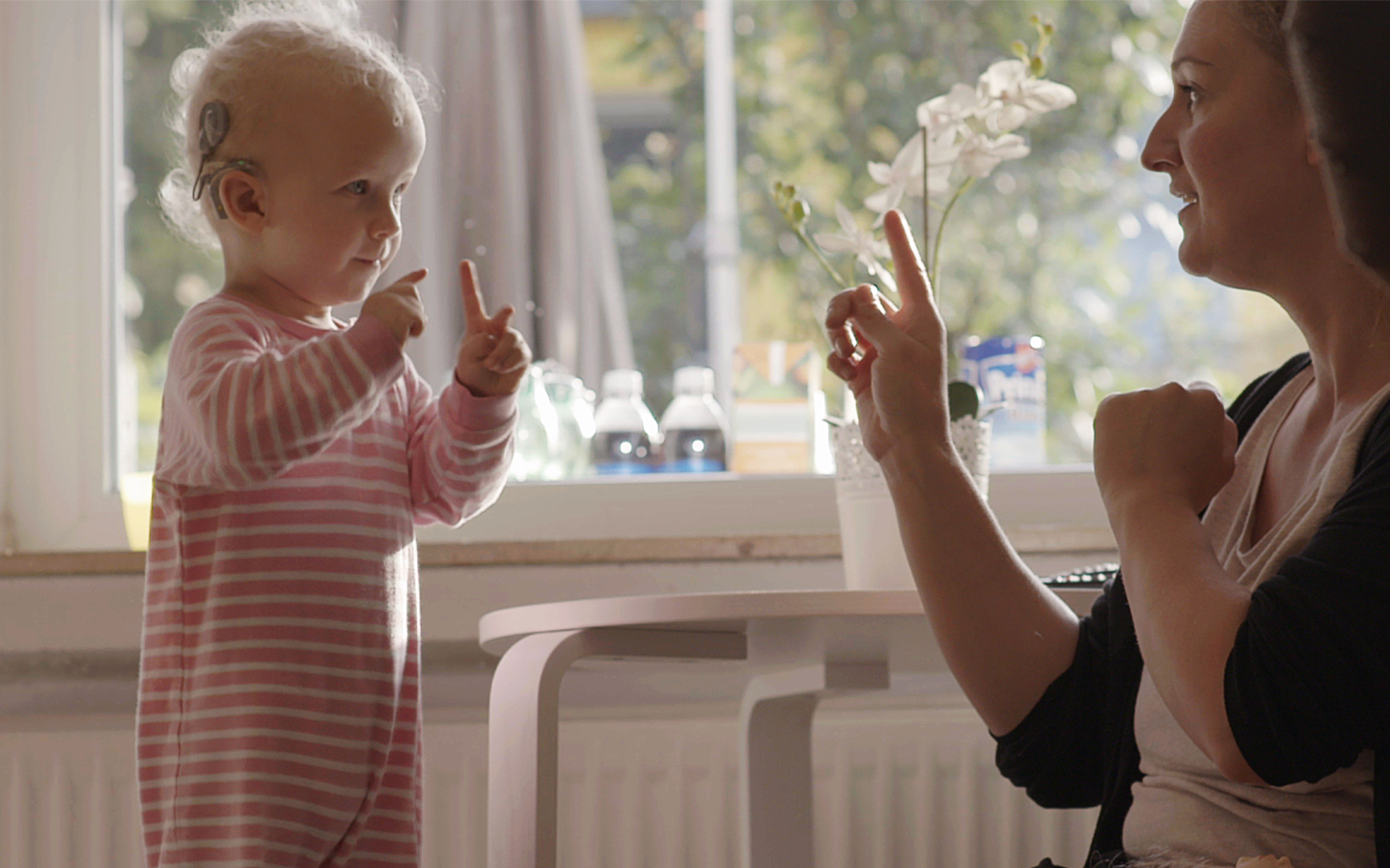 Una mujer interactúa con un niño pequeño que lleva un implante Cochlear