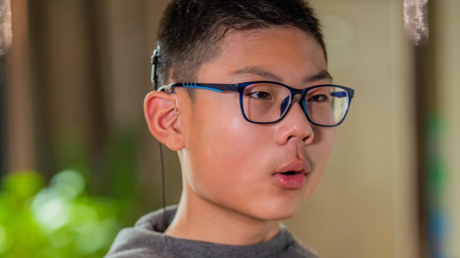 A boy wearing an implant practices his speech therapy