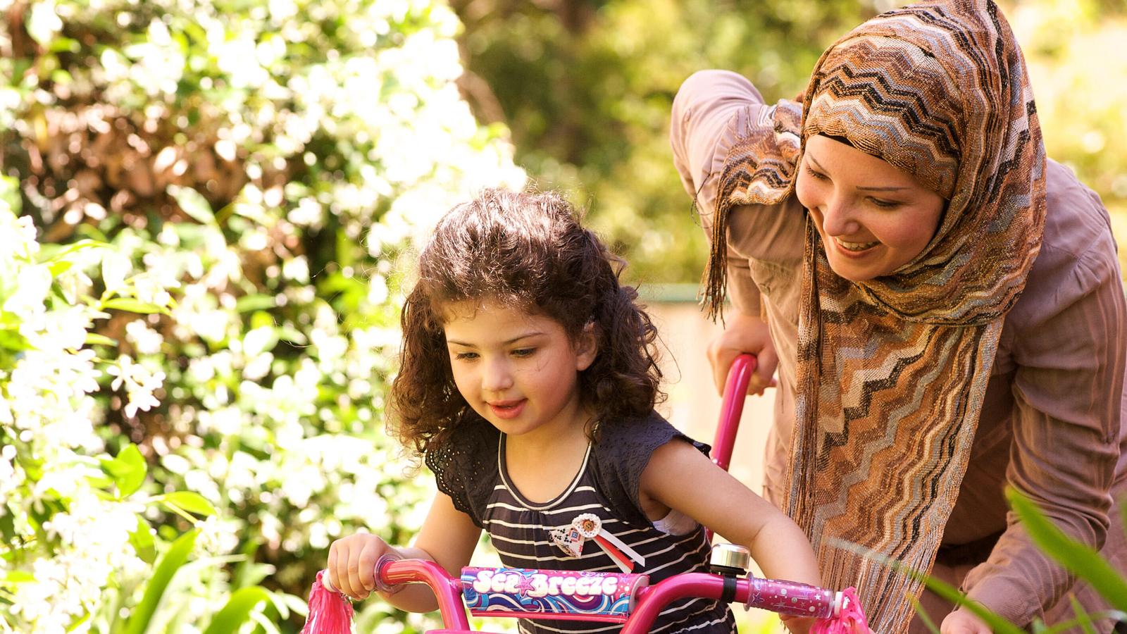 Una mujer ayuda a una niña a ir en bicicleta