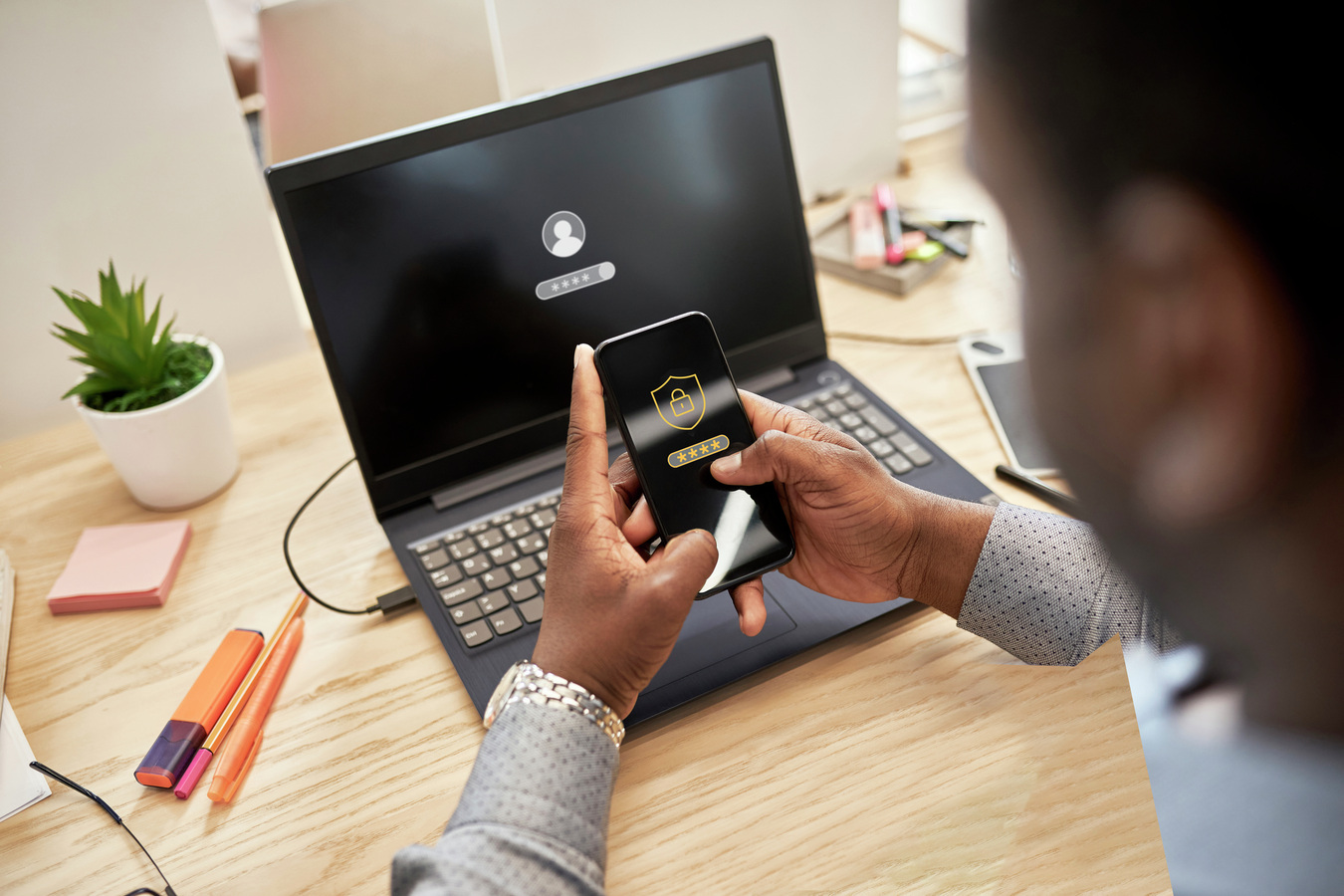 A man sitting at his desk, using a multi-layer authentication method to log in to his account on his laptop.