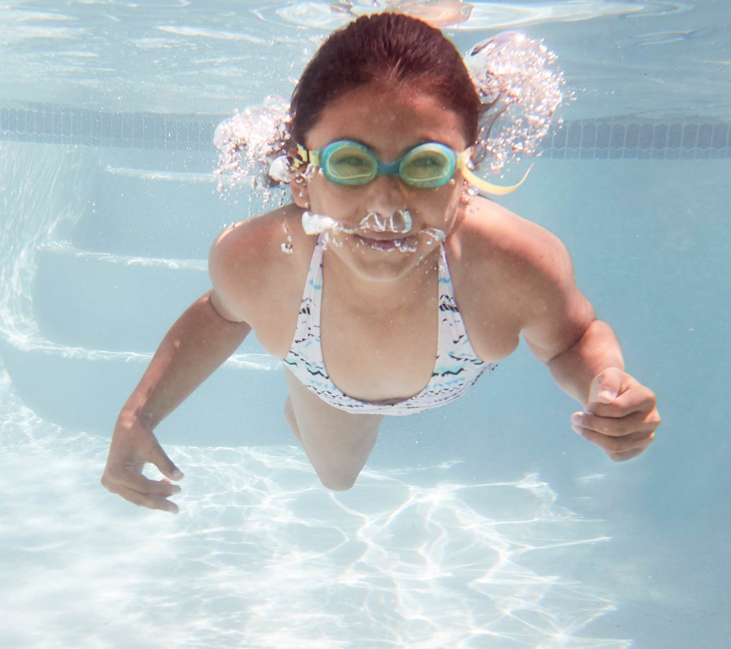 Dítě plave pod vodou s implantátem Cochlear