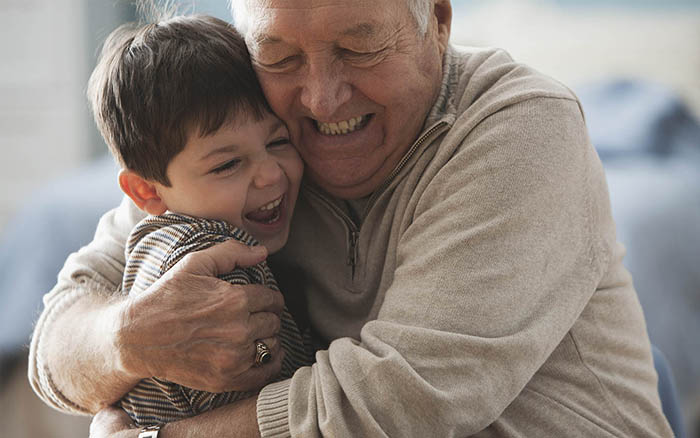 Grand-père avec un implant Cochlear câlinant son petit-fils
