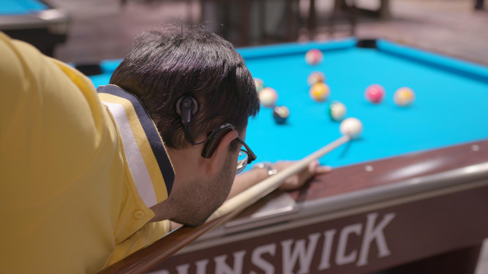Adult man wearing an implant plays snooker