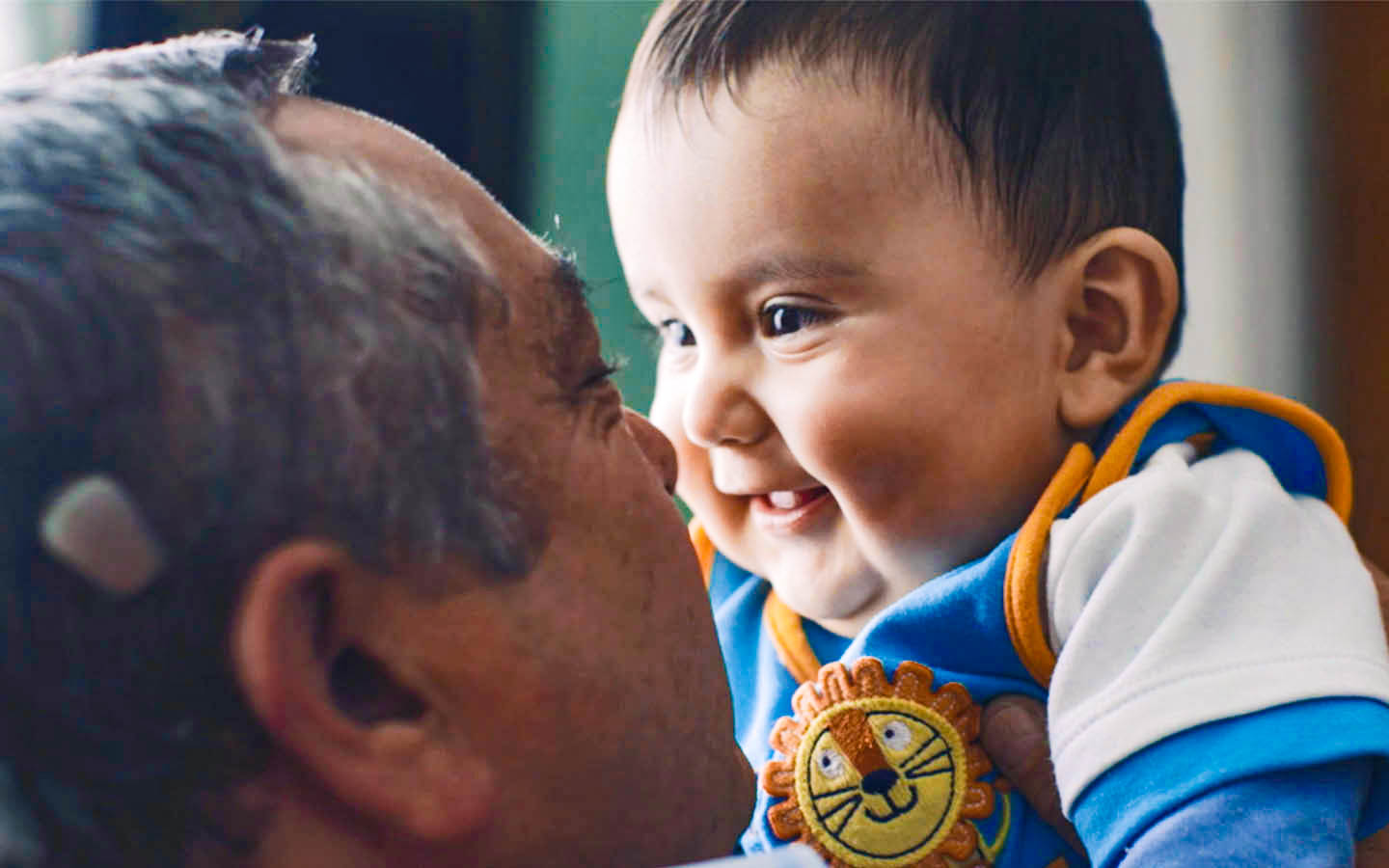 A man holds up his smiling grandson